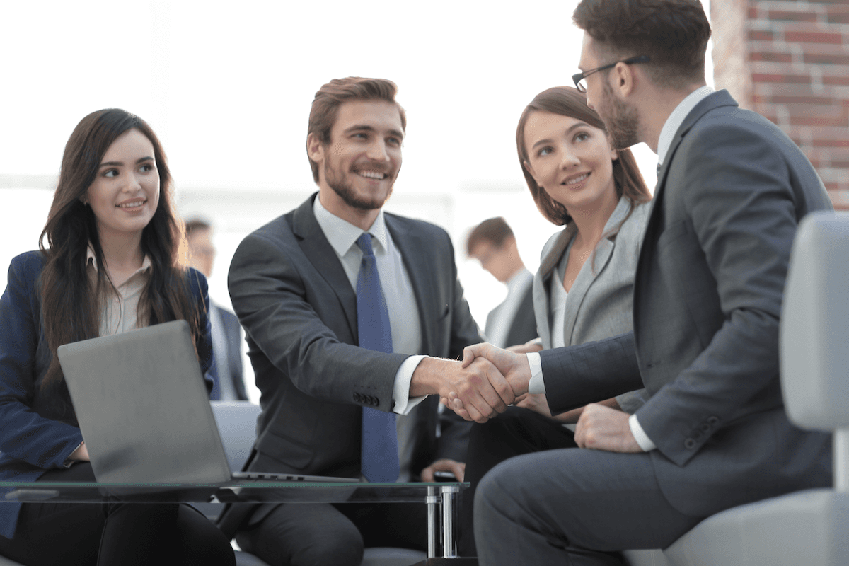 client vs customer: Two men smiling while shaking hands