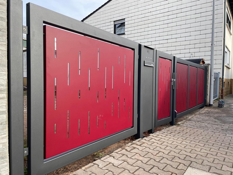 Metalltor in Schwarz und roten Elementen für eine Einfahrt.