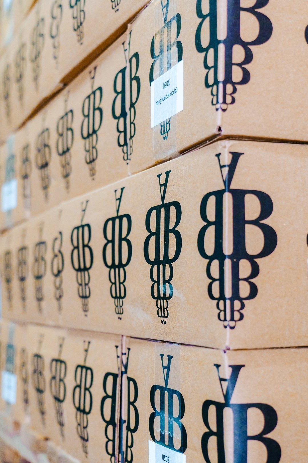 Stacks of cardboard boxes printed with black logos fill the frame, forming a repeating pattern.