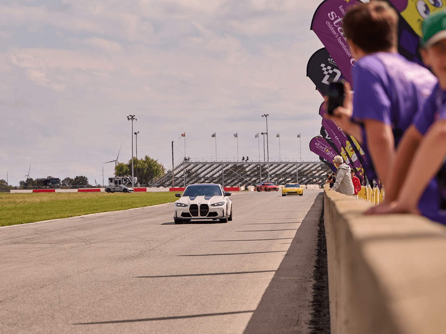Cars on the track beside Starlight Canada flags at Drive For Smiles Toronto 2025.