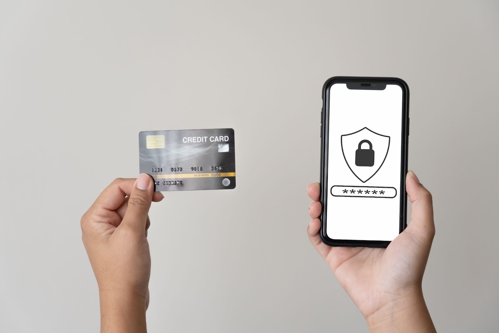 A person holding a credit card and a cell phone with a lock symbol on the screen. 