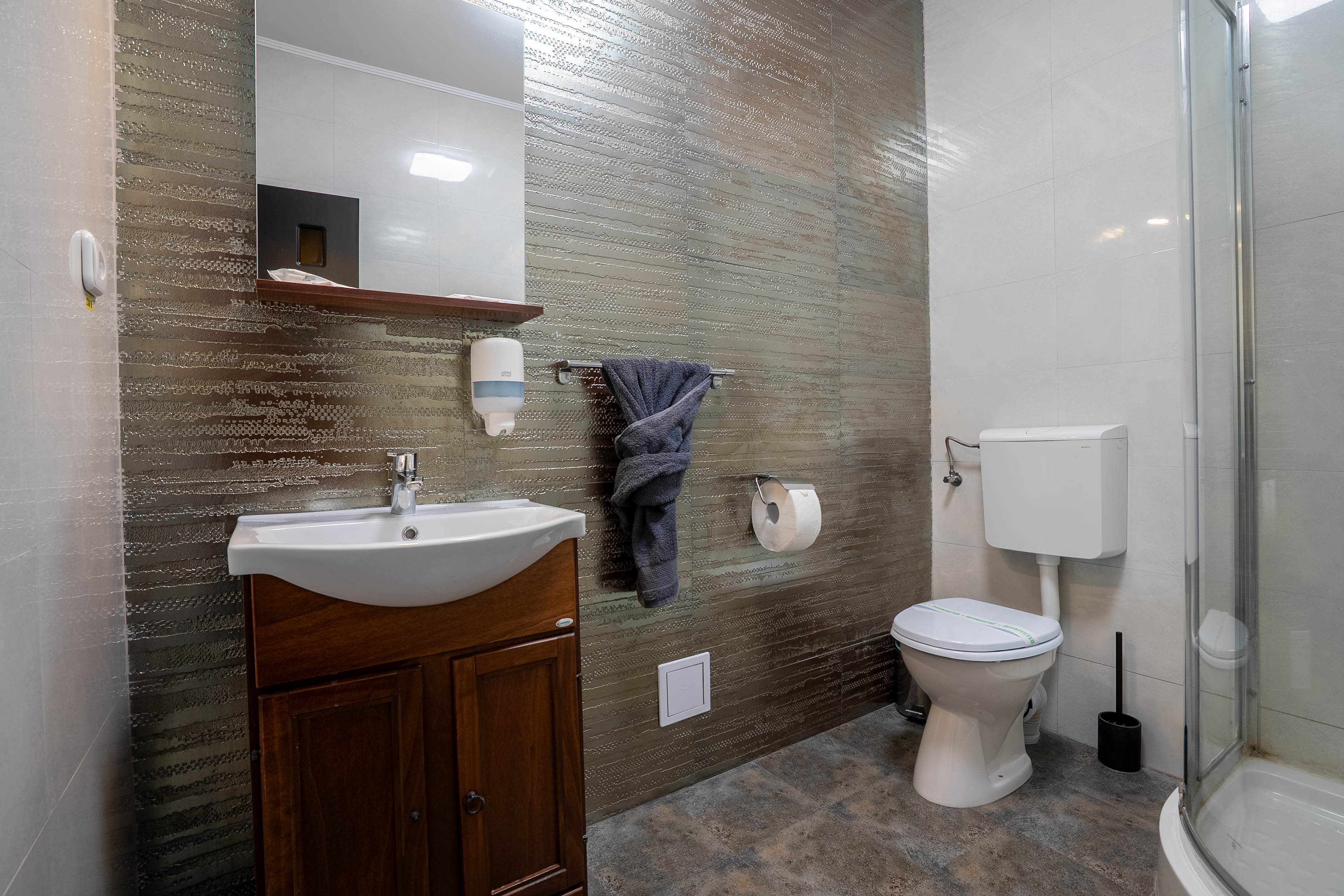 A serene outdoor lounge area with two chairs surrounded by lush greenery and natural light streaming in.