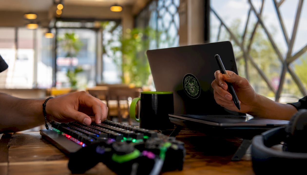 Overhead view of hands using gaming keyboard and tablet