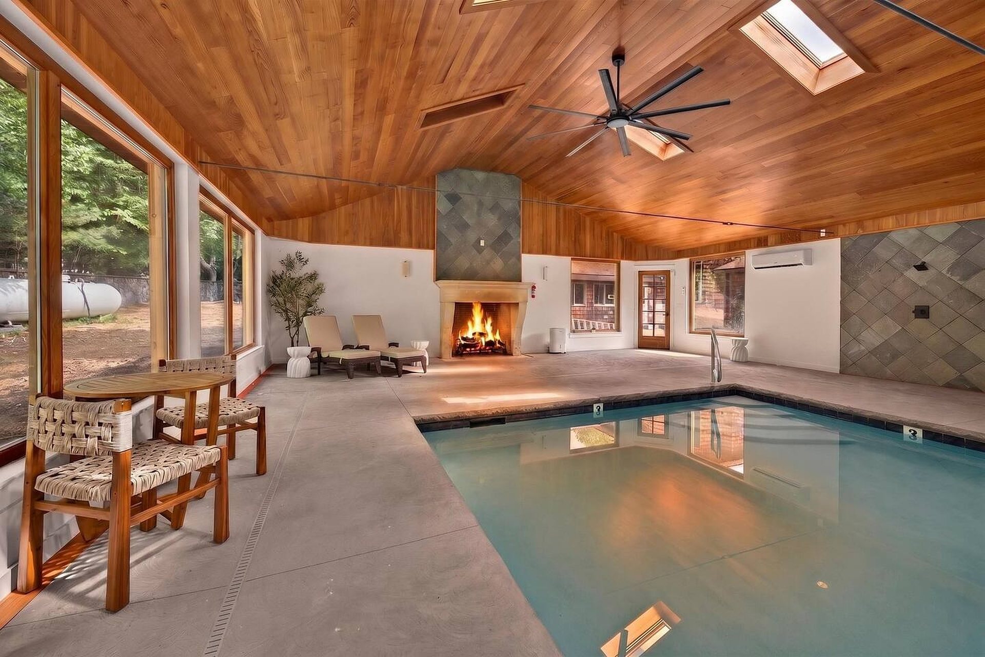 Pool hall with a fieldstone fireplace, lounge chairs and skylights