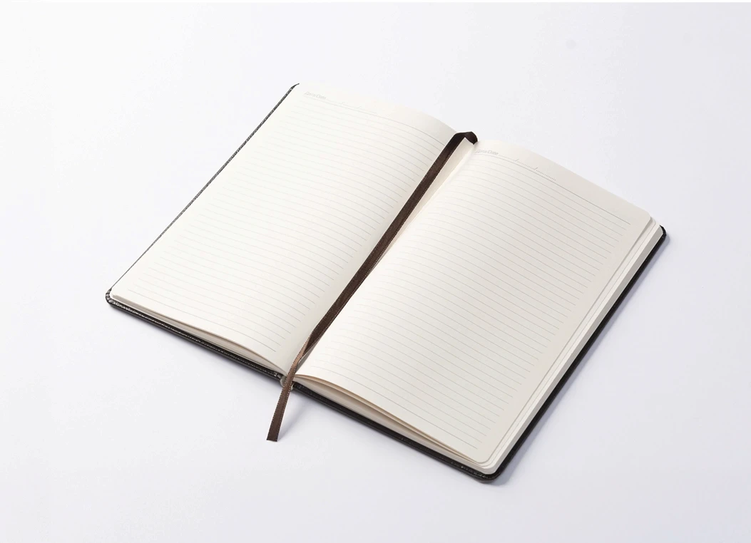 Open leather journal showing ruled ivory pages with ribbon bookmark