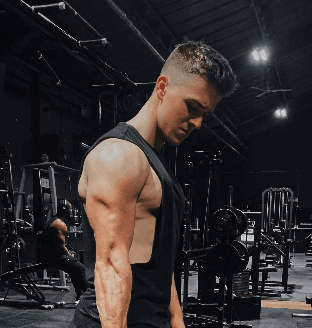 man in black tank top holding black dumbbell
