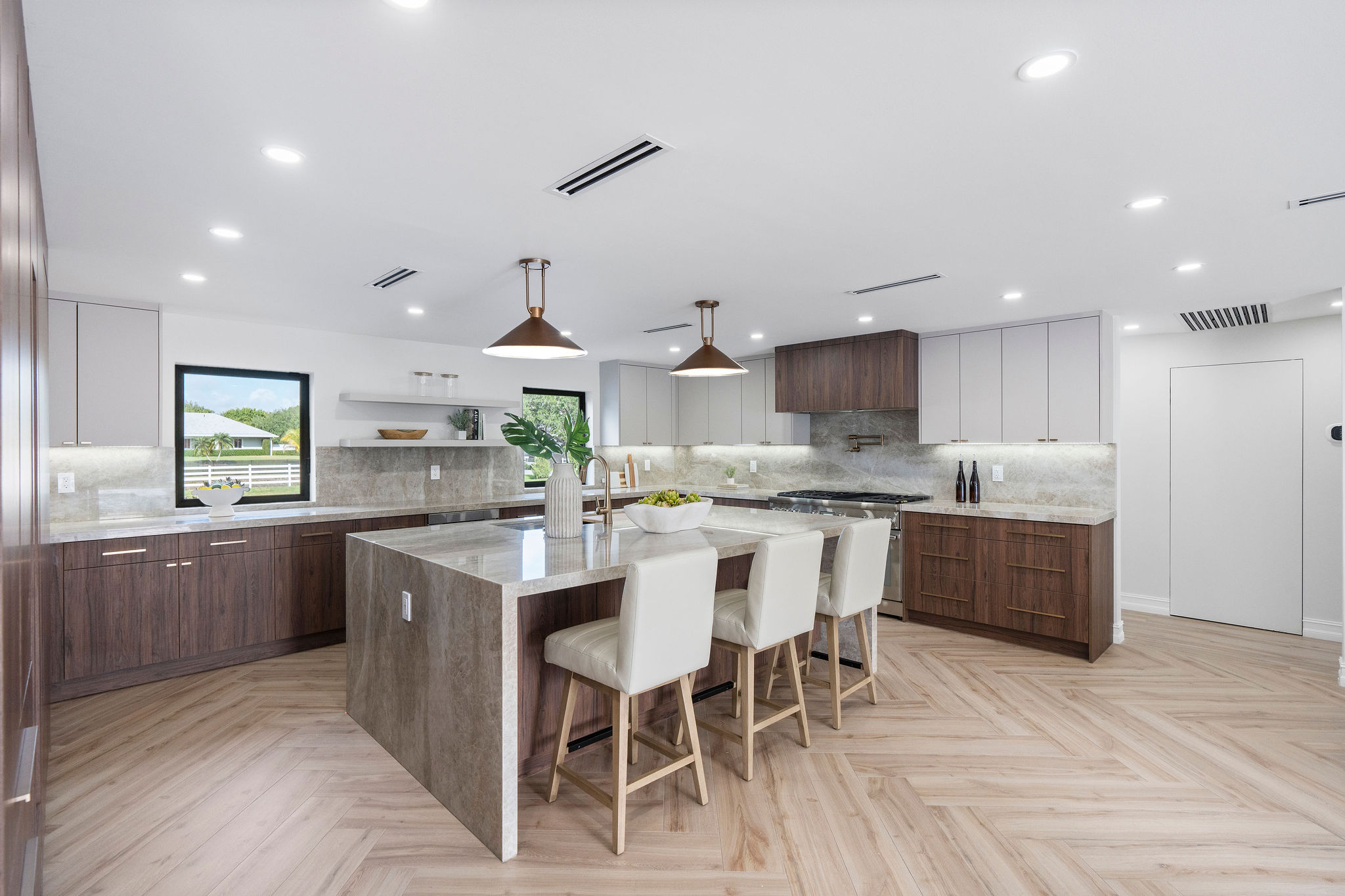 Modern kitchen with island, bar stools, pendant lights, and wood cabinets.