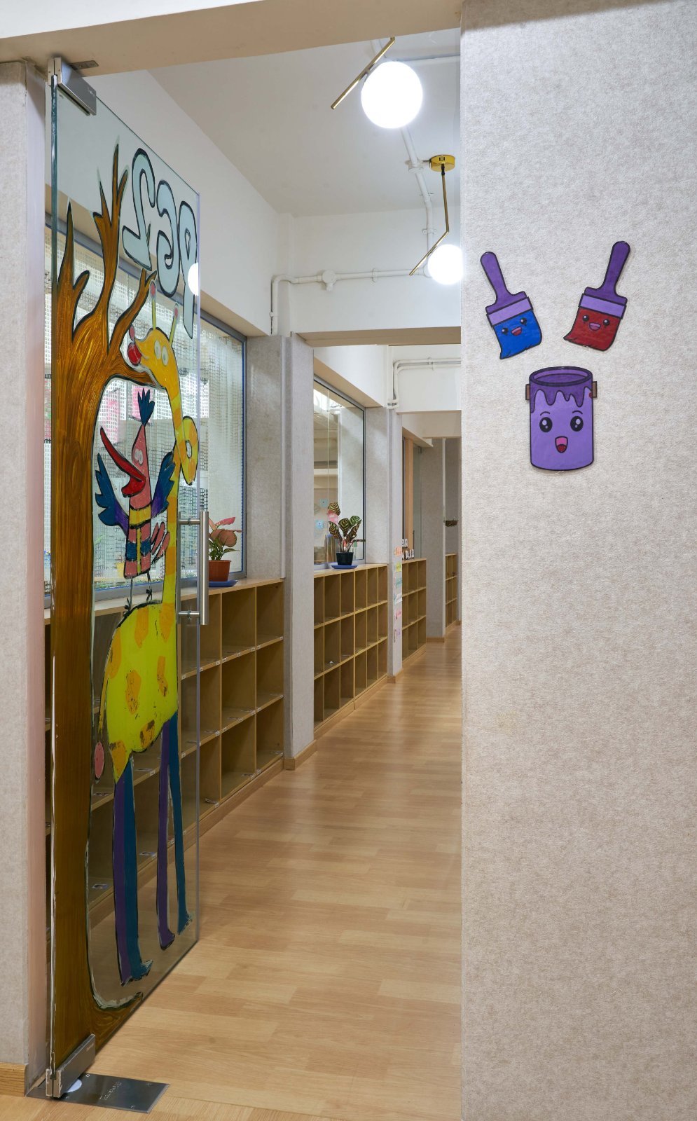 Nature-inspired preschool entrance with sculptural tree partitions and suspended green leaf ceiling panels.