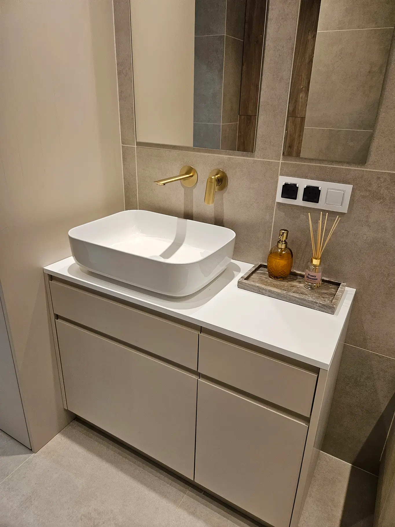 Kompaktowa szafka podumywalkowa z białym blatem i elegancką złotą baterią ze ściany.