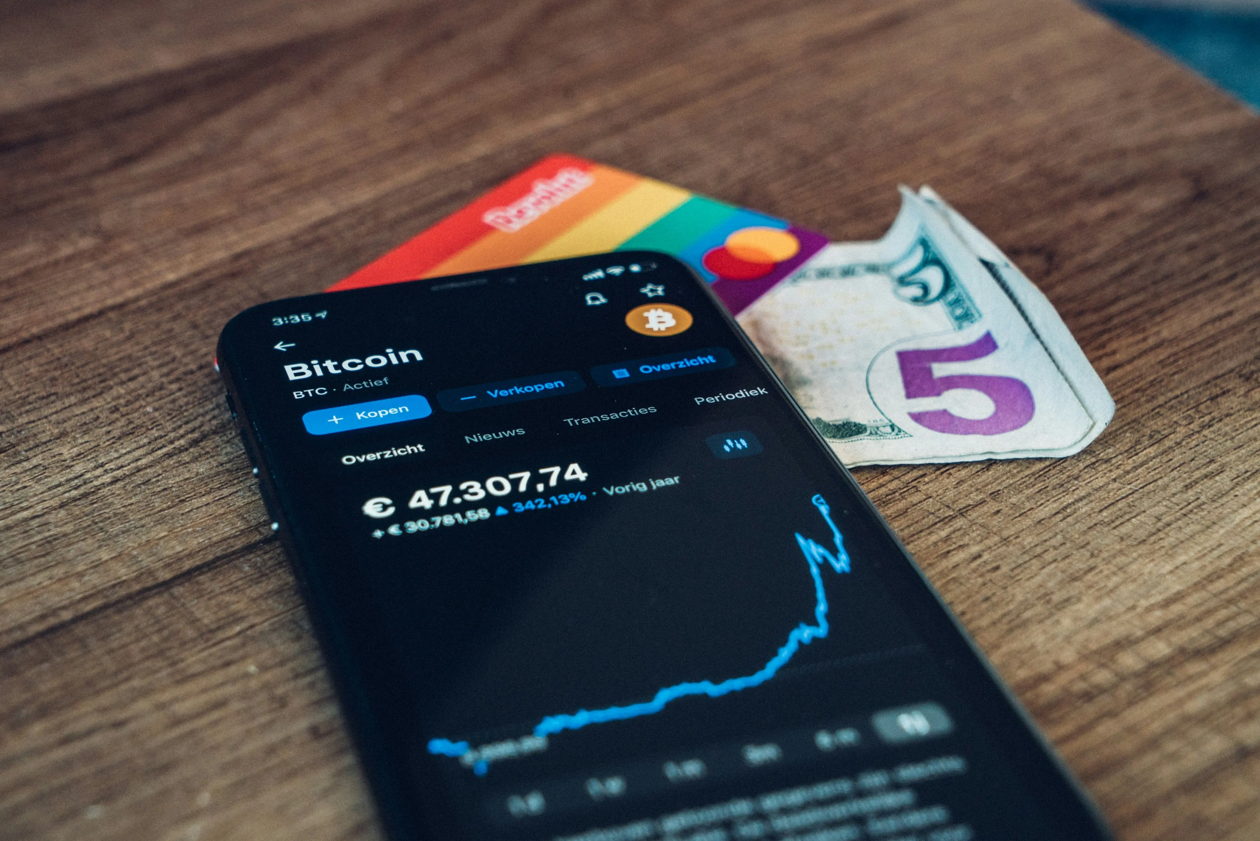 Smartphone displaying Bitcoin price with cash, resembling cryptocurrency investing.