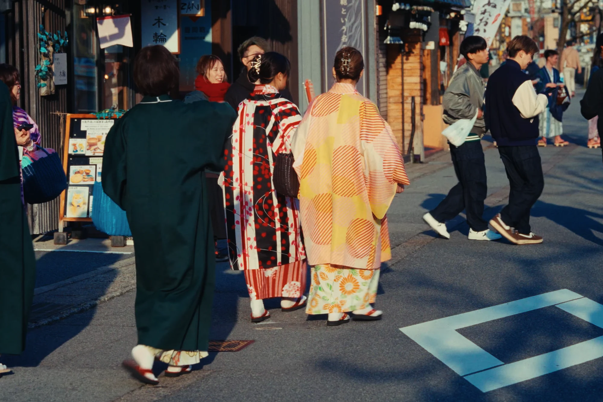 A group in yukata and haori walking a Kinosaki street in autumn.