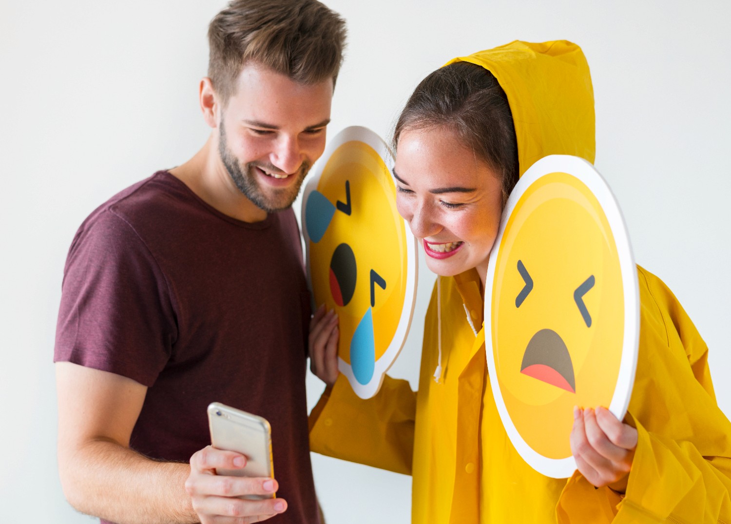 A man and woman joyfully display emoticons, showcasing a range of emotions in a vibrant and engaging manner.