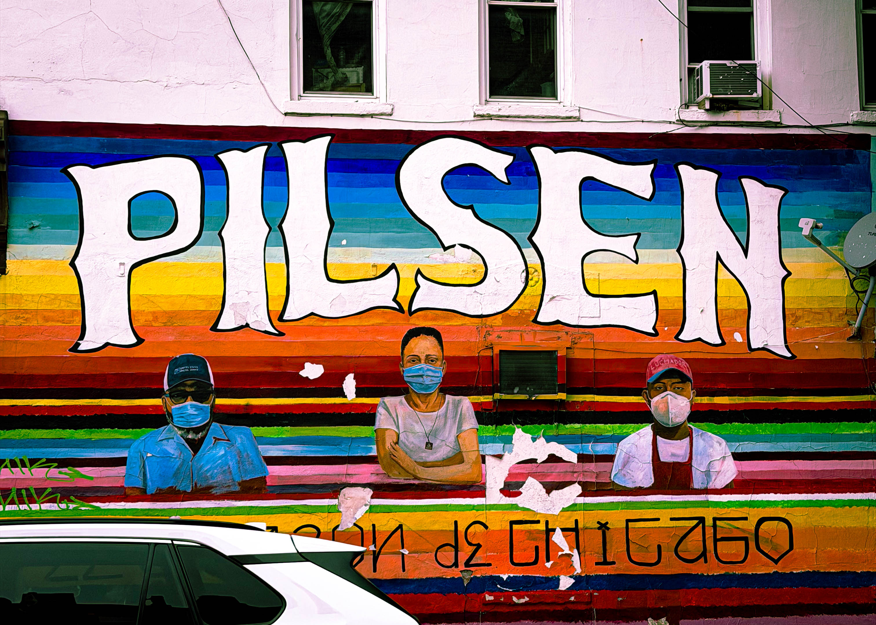a mural for the neighborhood of pilsen in bright colors with people wearing medical masks