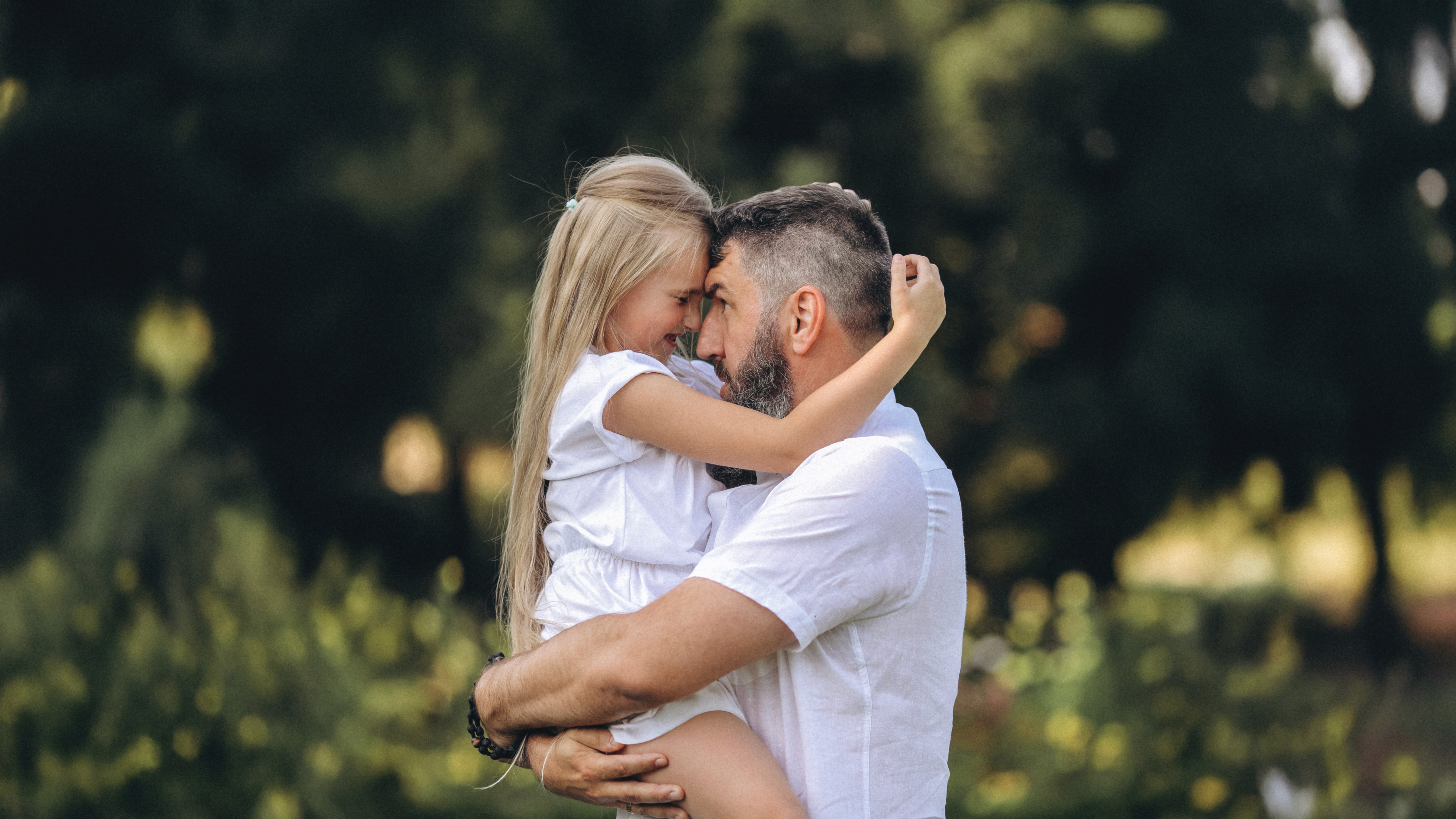 Dad holding his young daughter in a warm, natural outdoor family session in San Diego.