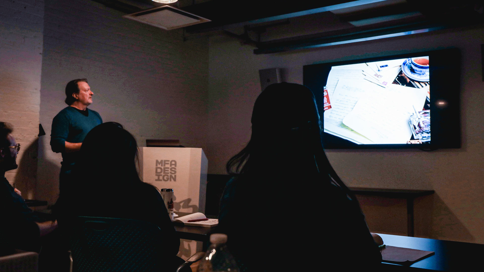 Ross MacDonald giving lecture in darkened classroom