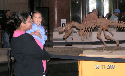 Young Alyssa with her mother, in front of a dinosaur skeleton.