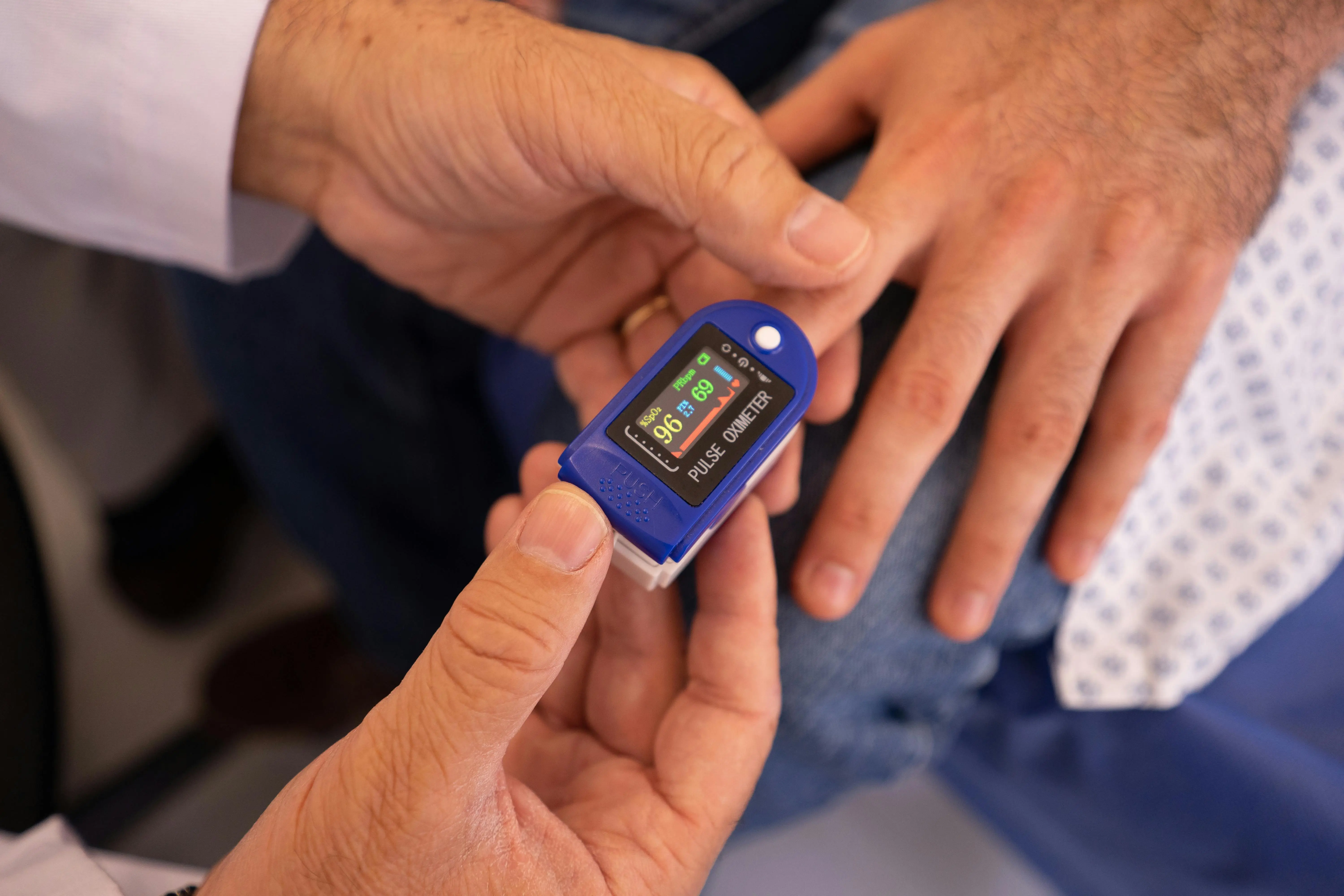 A senior getting their pulse checked by a pulse oximeter.
