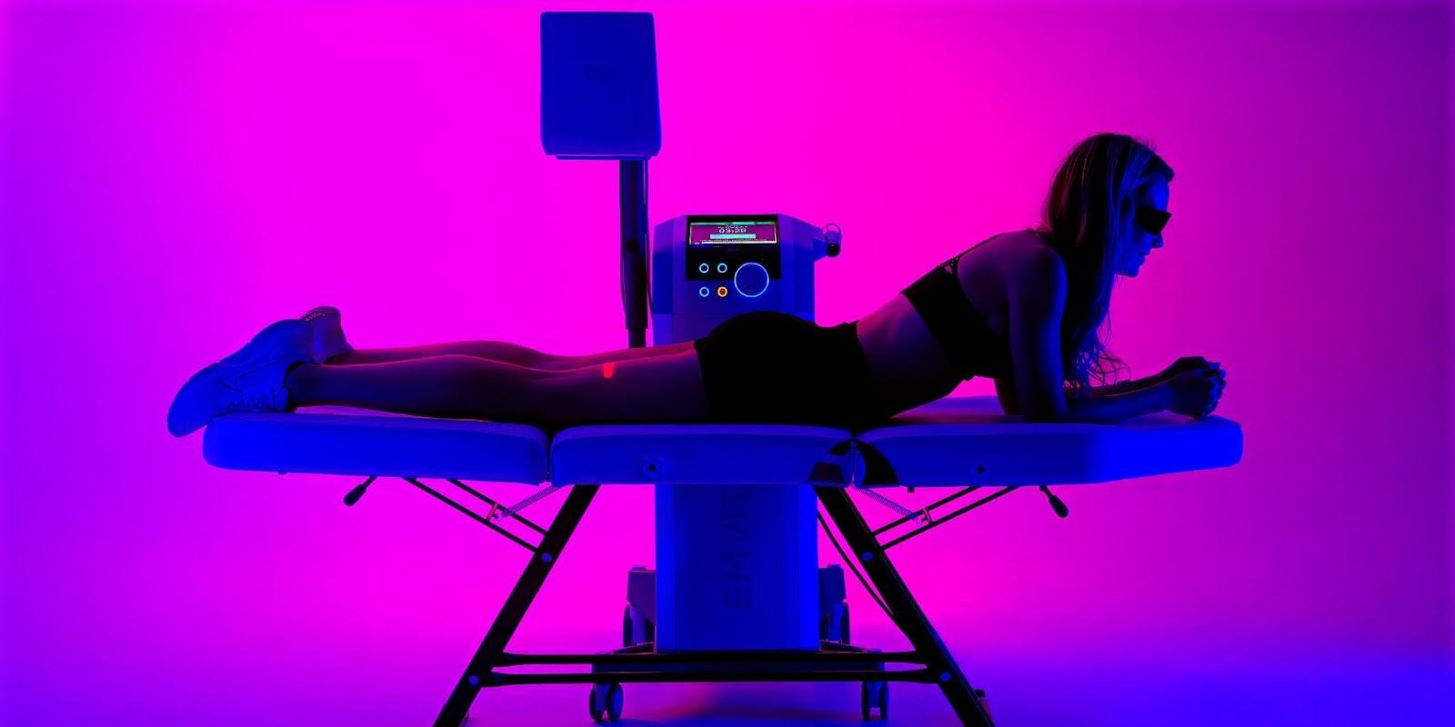 A woman is positioned on a table with blue light, experiencing a functional wellness therapy session at My Dental Touch Wellness Studio.