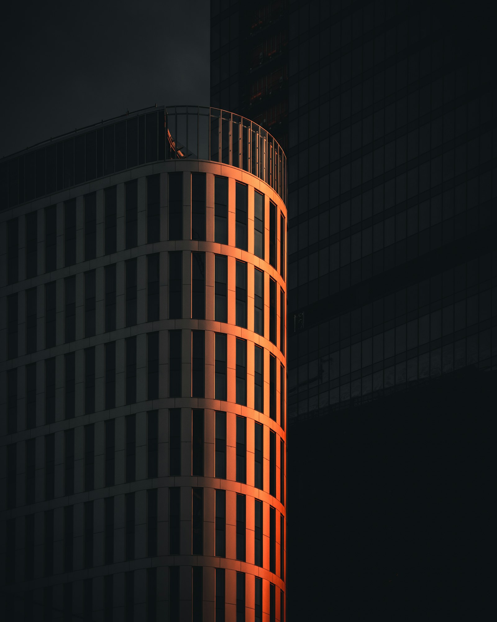 Curved high-rise with a warm edge of light at night