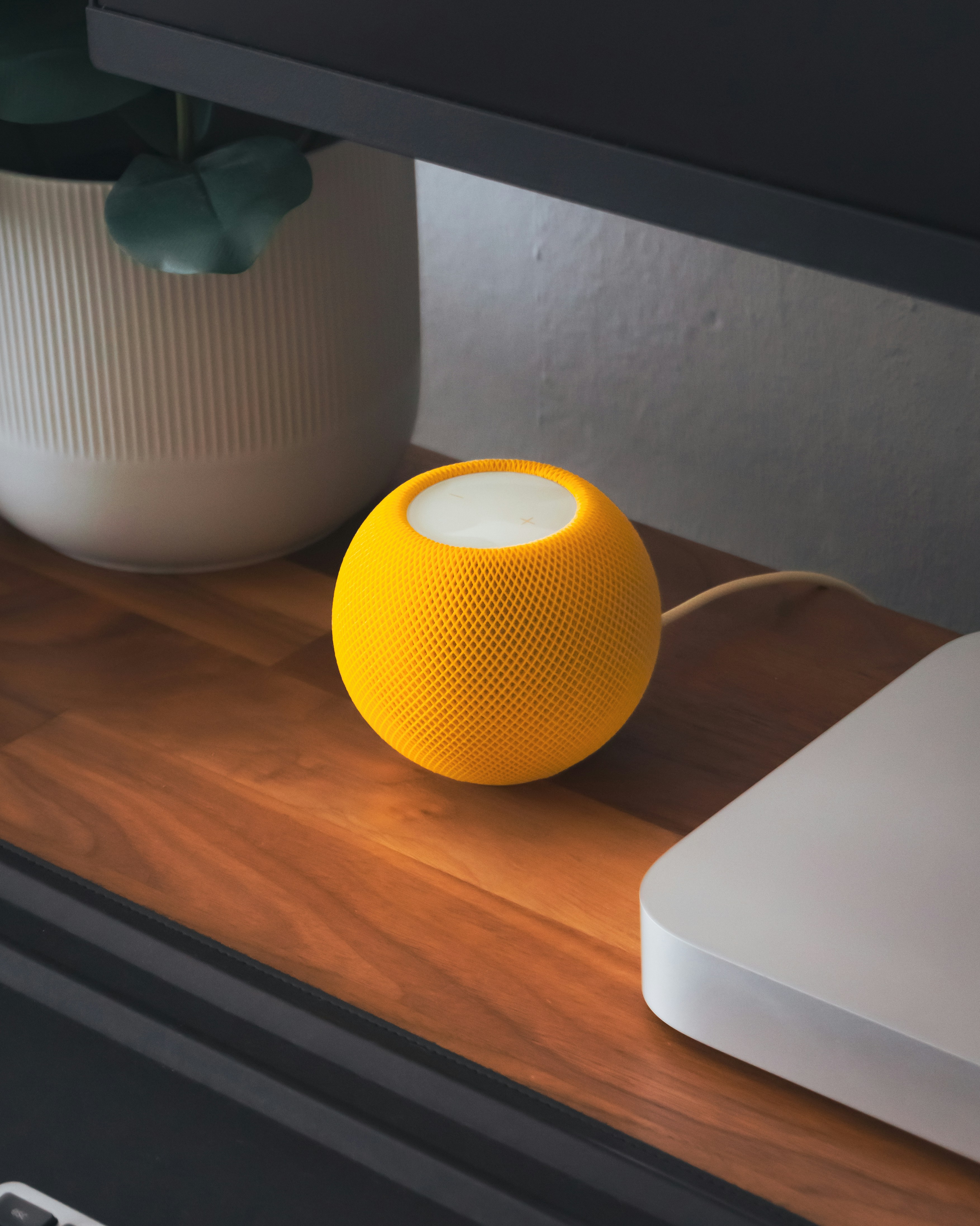 A yellow speaker sitting on top of a wooden table