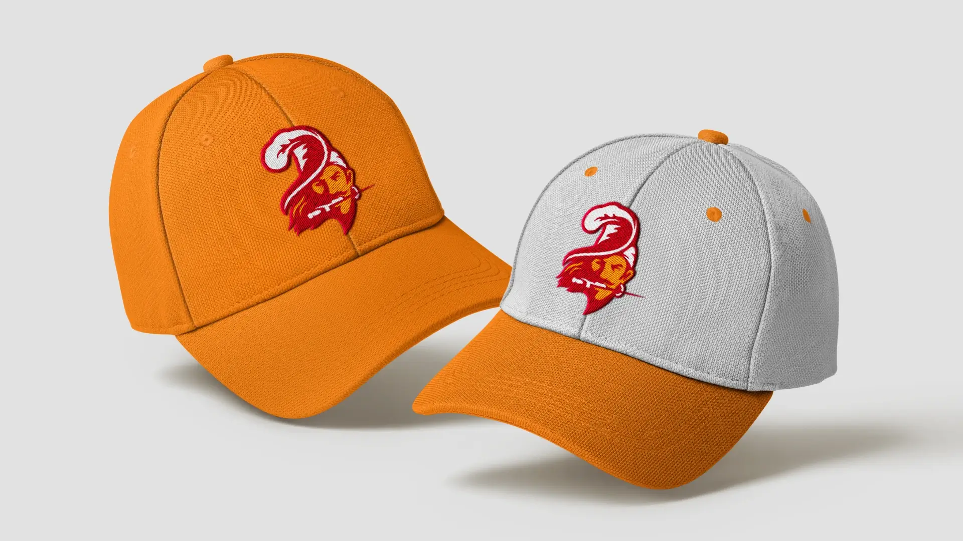 Two hats floating on a gray background with the new buccaneers logo embroidered. One is light orange and the other is white with an orange brim.