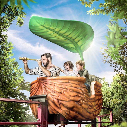 一个男人和两个孩子乘坐坚果形状的车厢在有叶子遮盖的轨道上行驶。男人通过望远镜观察,而孩子们则面带微笑。