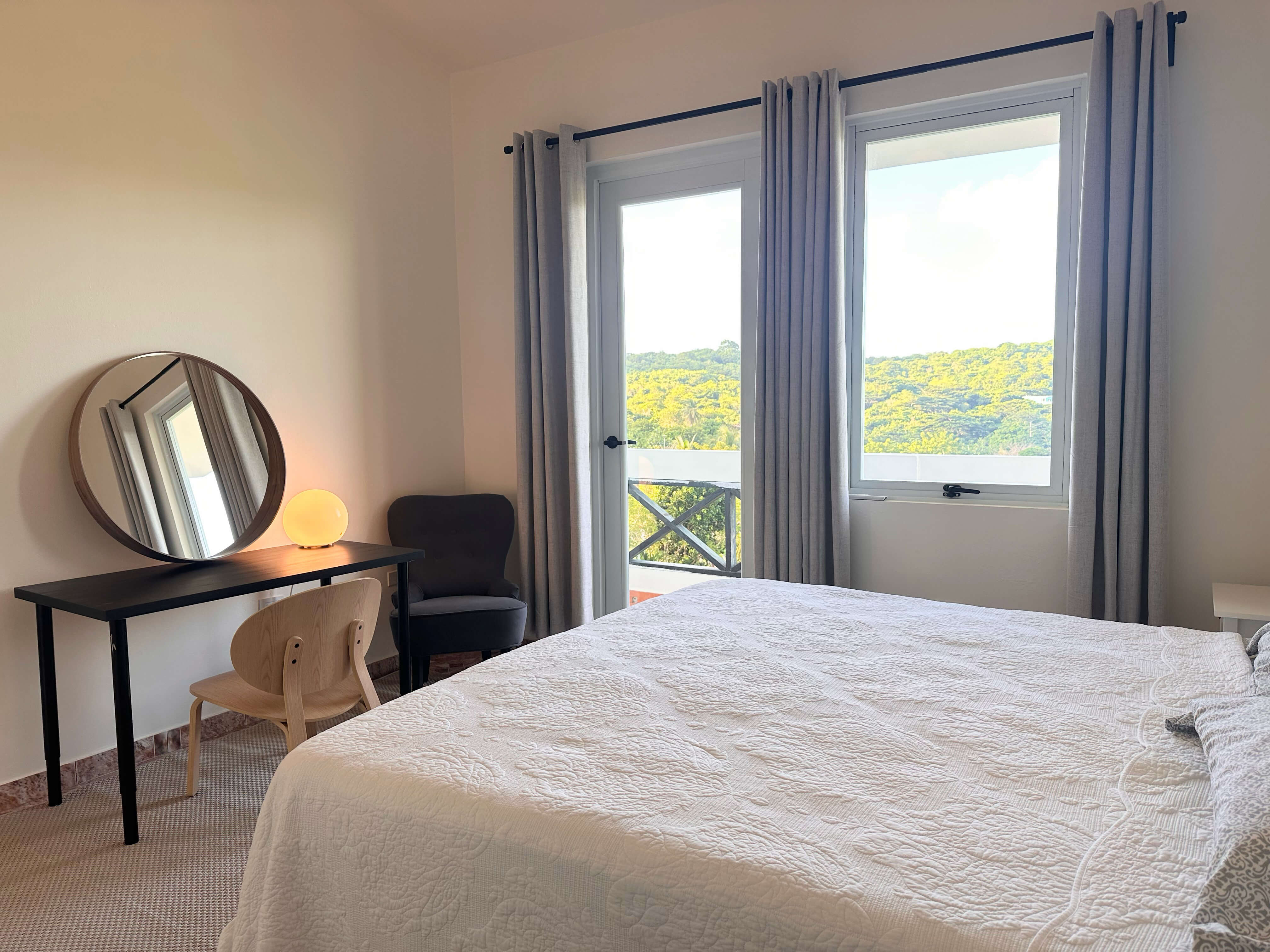 Room 9 bedroom featuring a queen bed, seating, and a tropical view through large windows.