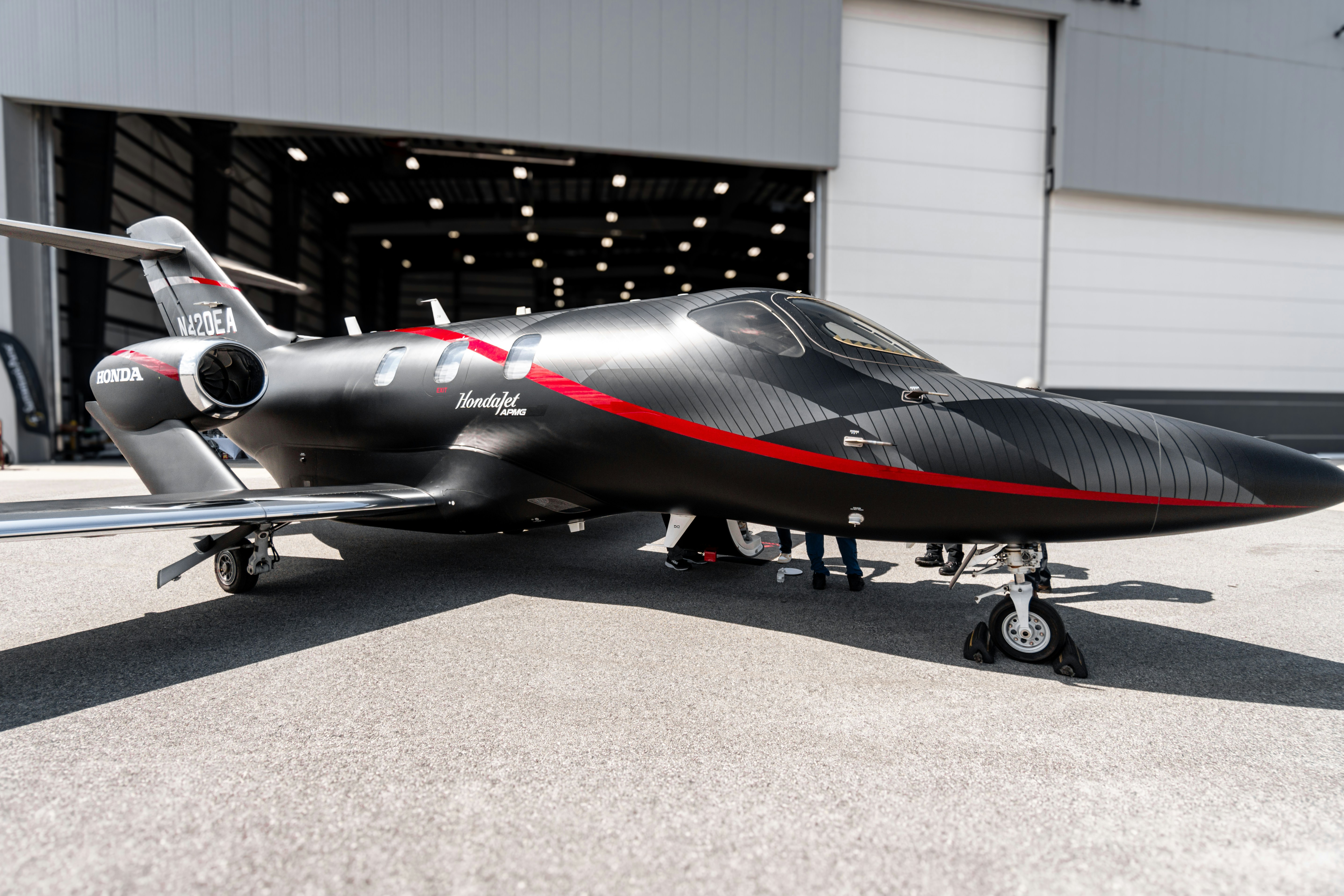 A black and red airplane parked in front of a garage