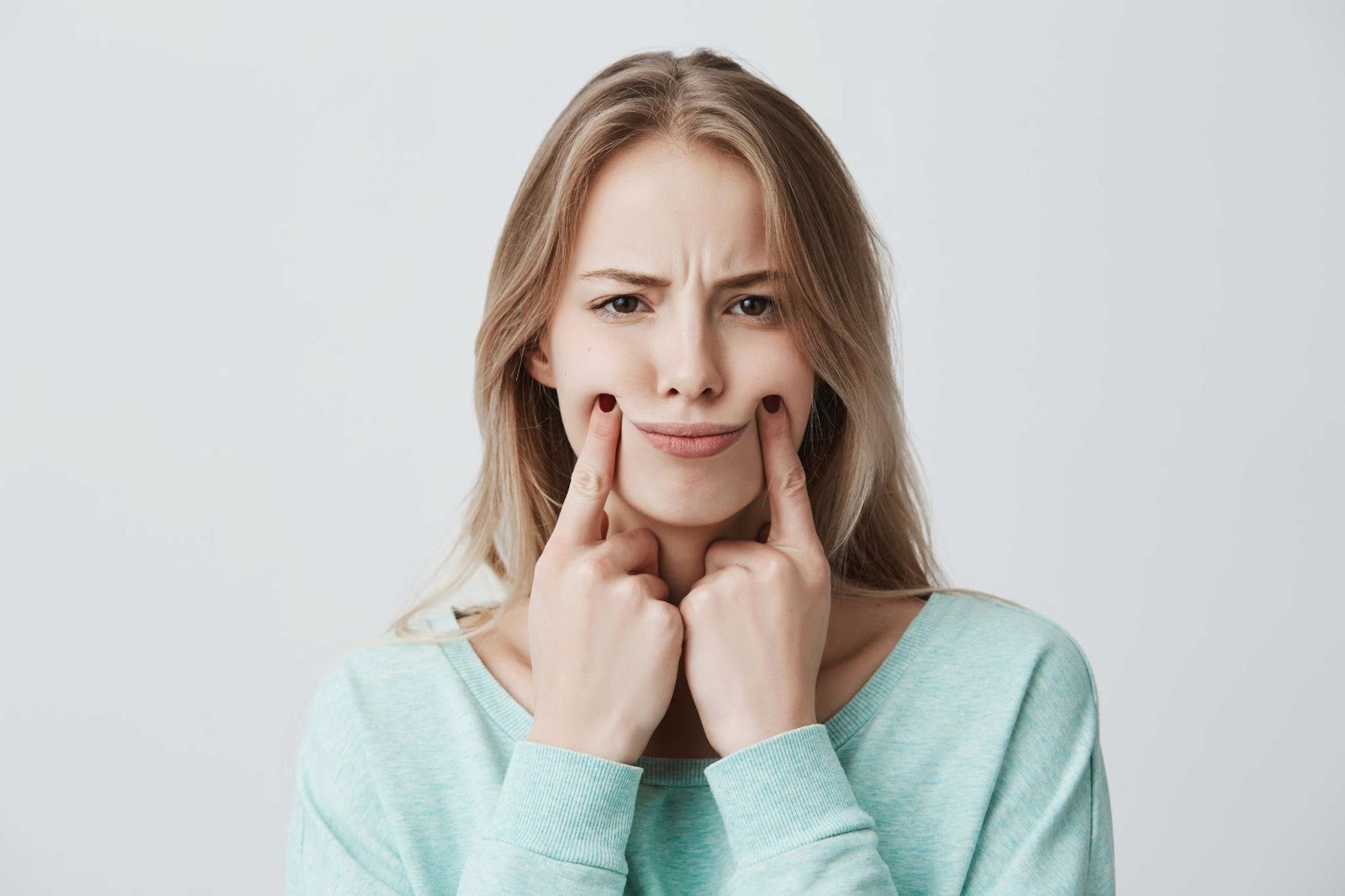 A girl in a thoughtful pose, resting her chin on her fingers.