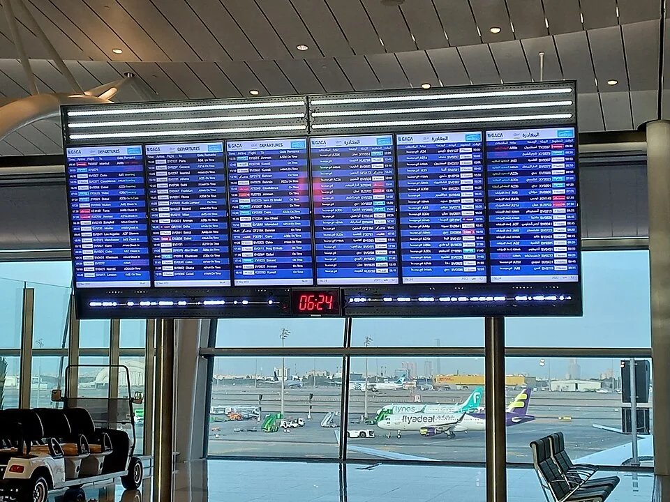 An airport flight information display showing departures and times.