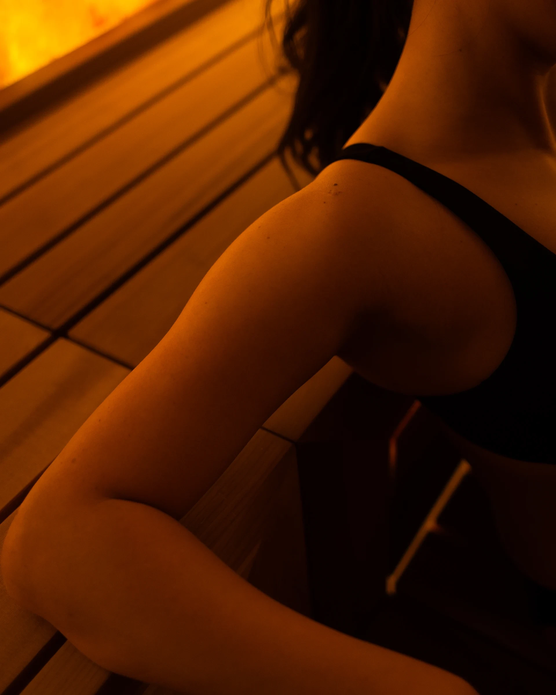 Closeup of someone's arm as they lean back on the cedar wood in Aetherhaus' Himalayan salt sauna.