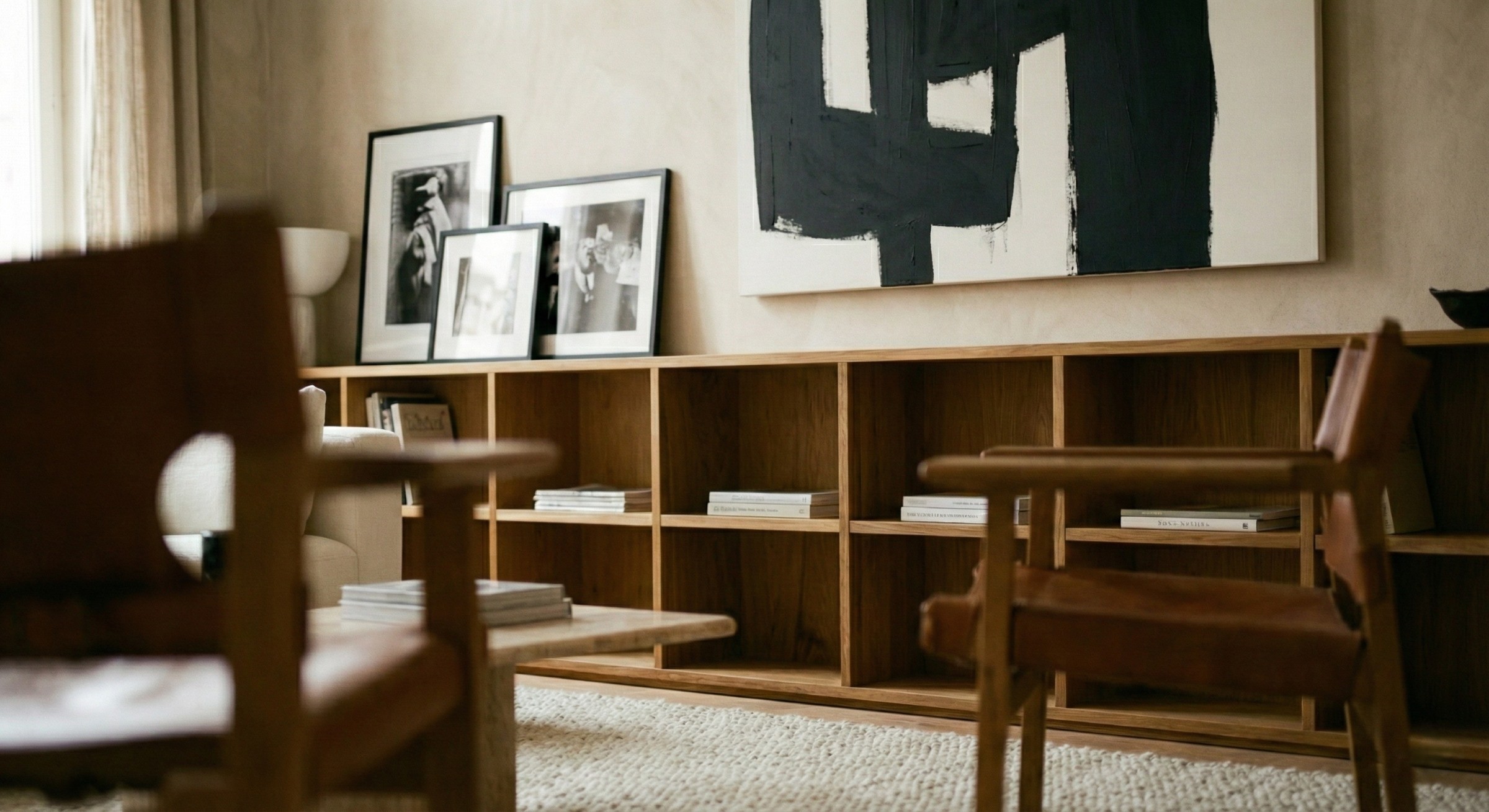 A cozy interior featuring wooden furniture, a modern art piece on the wall, and framed pictures on a shelf.