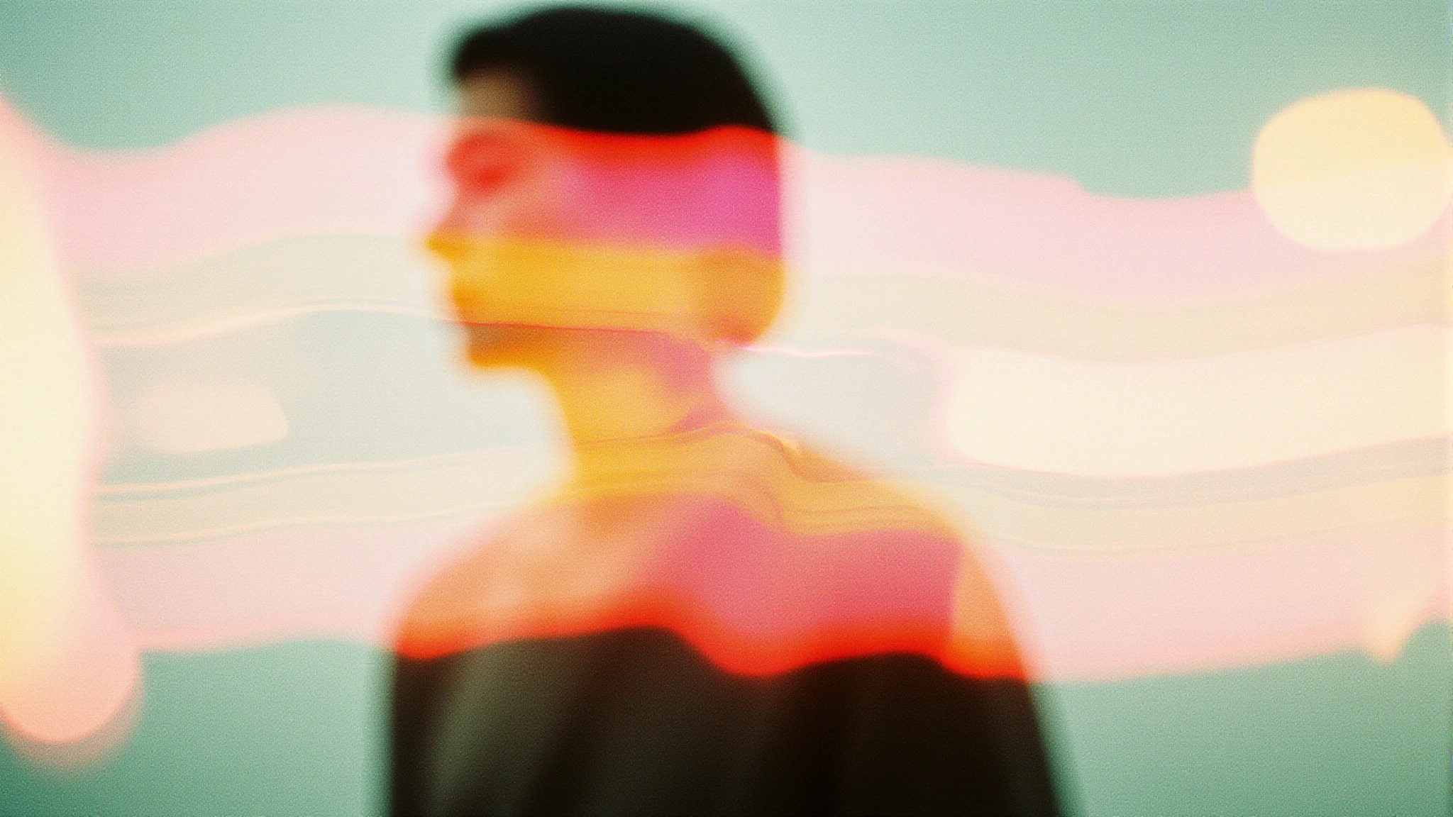 A blurred figure with vibrant streaks of pink, orange, and yellow light on a pastel green background.