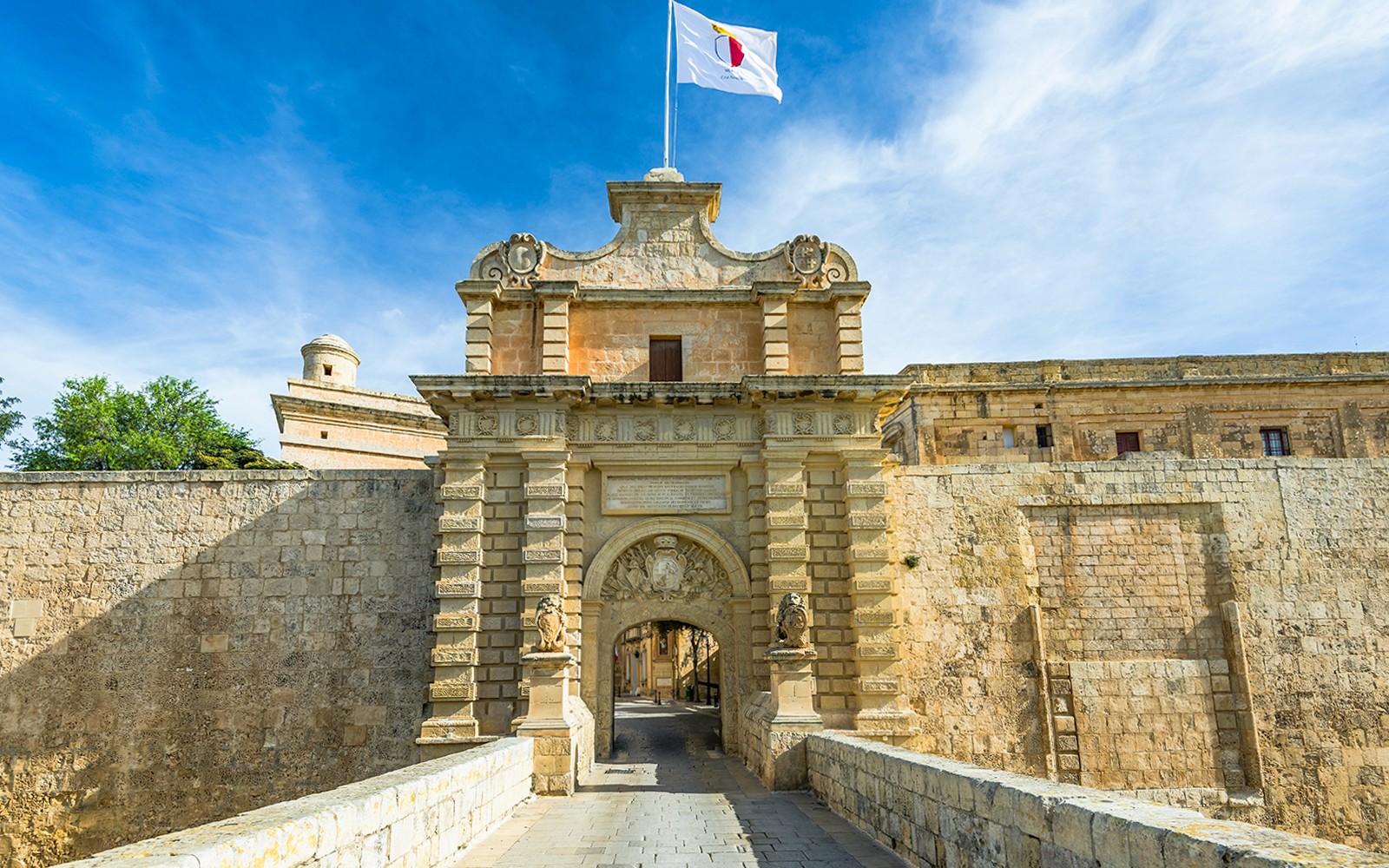 Main gate of Mdina, Malta, with stone archway and flag, seen on a guided tour of Mdina and Rabat.