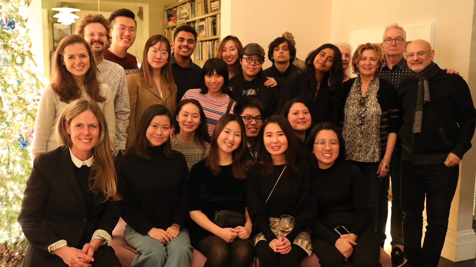 students and teachers pose by christmas tree