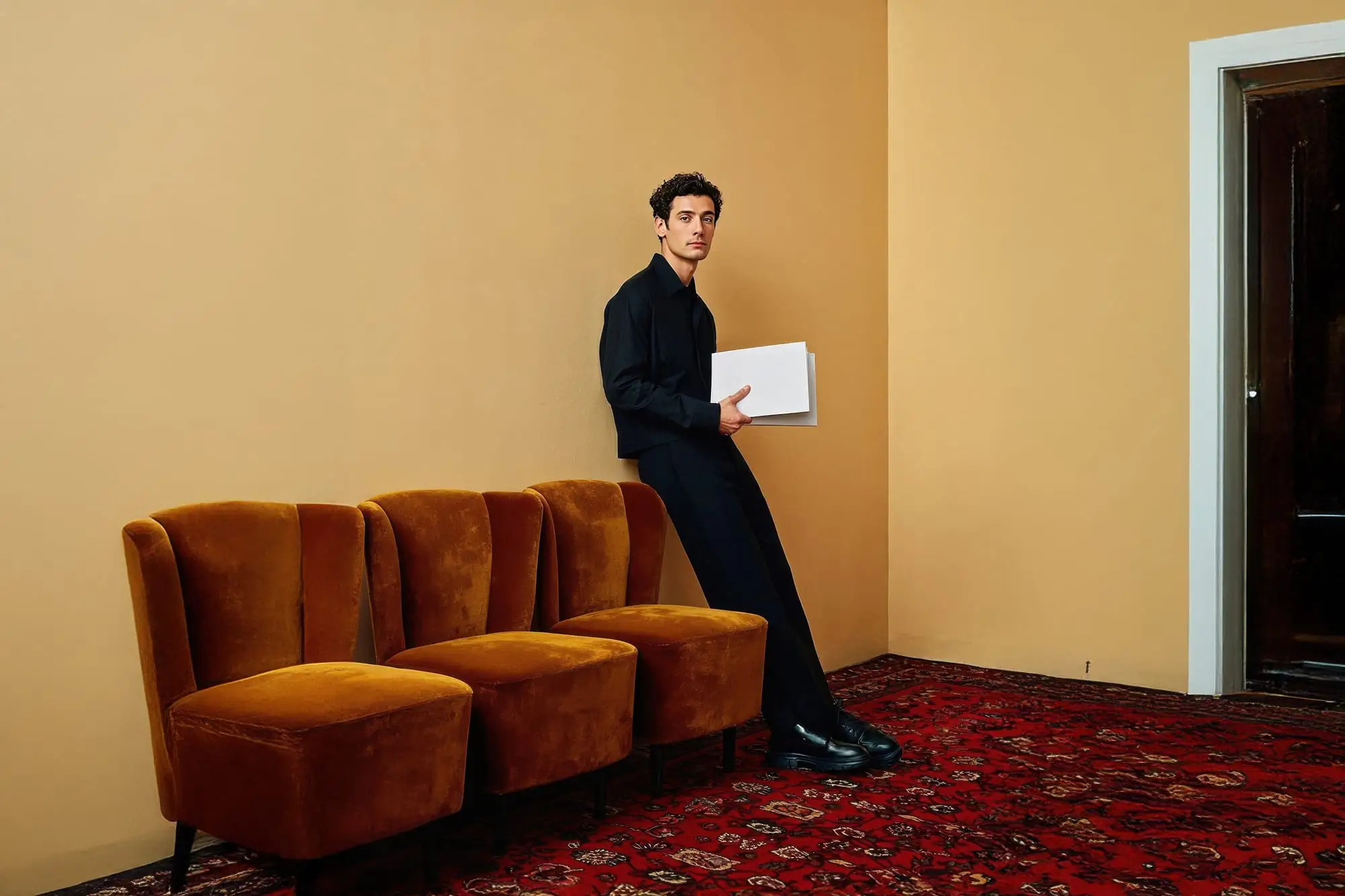 A man sitting against the wall holding a folder