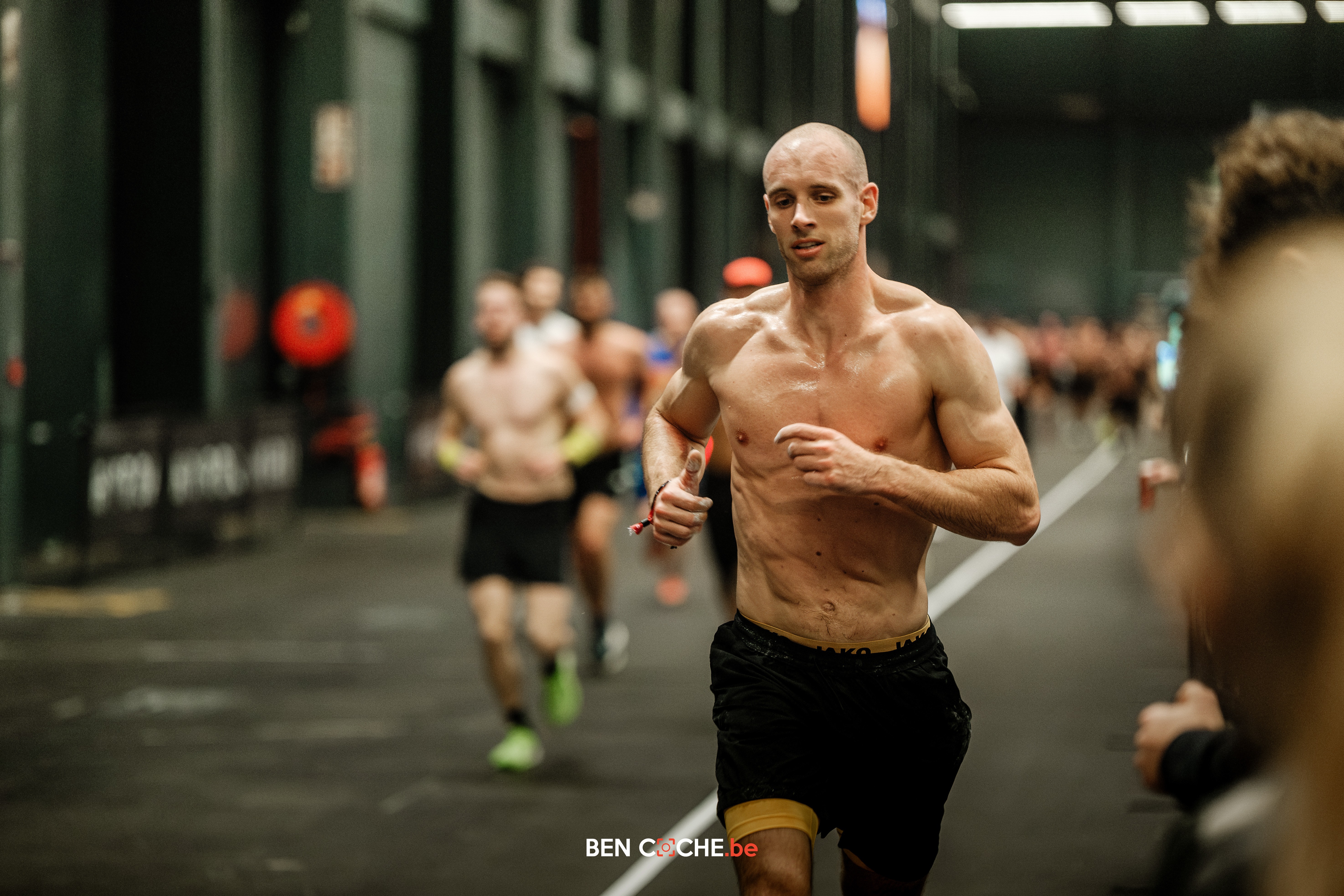 Two individuals are working out in a gym, focusing on dumbbells and strength training equipment.