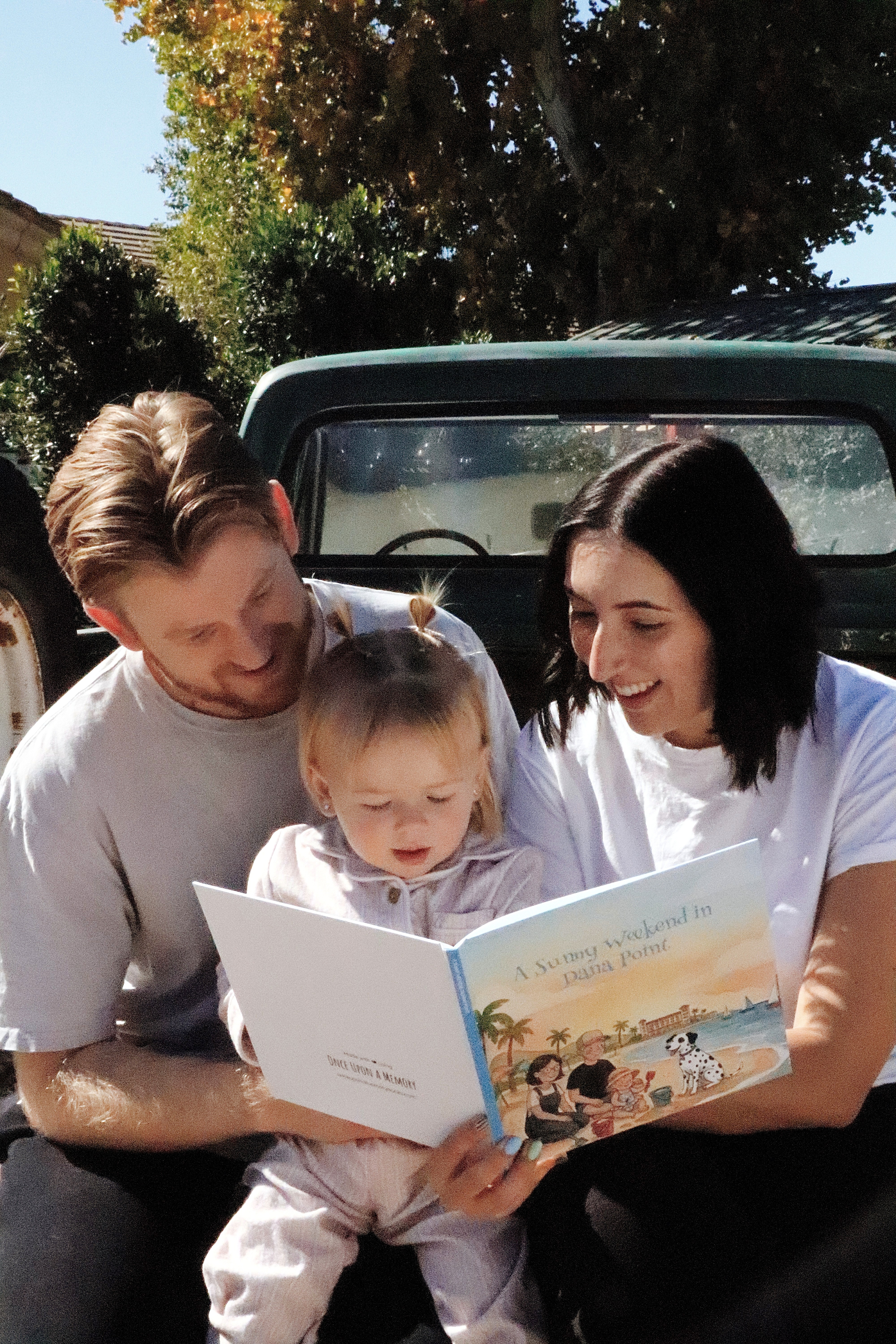 A smiling young man with crossed arms, wearing a plaid shirt and white t-shirt, poses against a dark background.