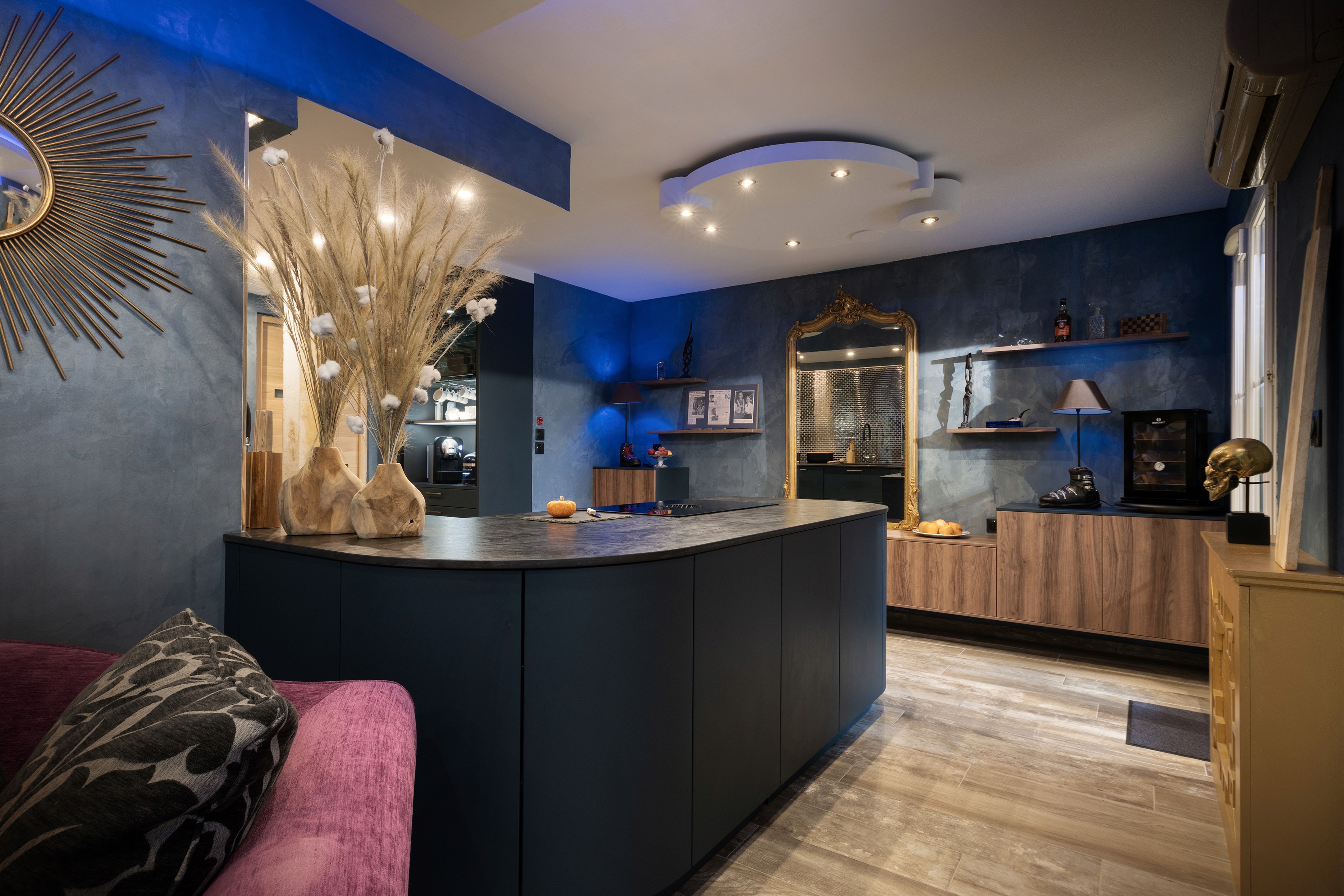 Transformation cuisine Seine-et-Marne avec armoires bois et bleu foncé, îlot incurvé élégant et canapé violet, rénovation 3 pièces complète.