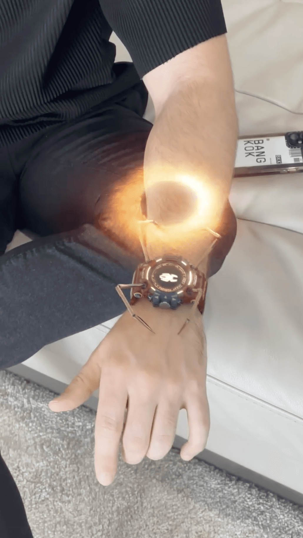 A futuristic G-Shock watch project a glowing, fiery hologram with spider legs over a user's wrist.
