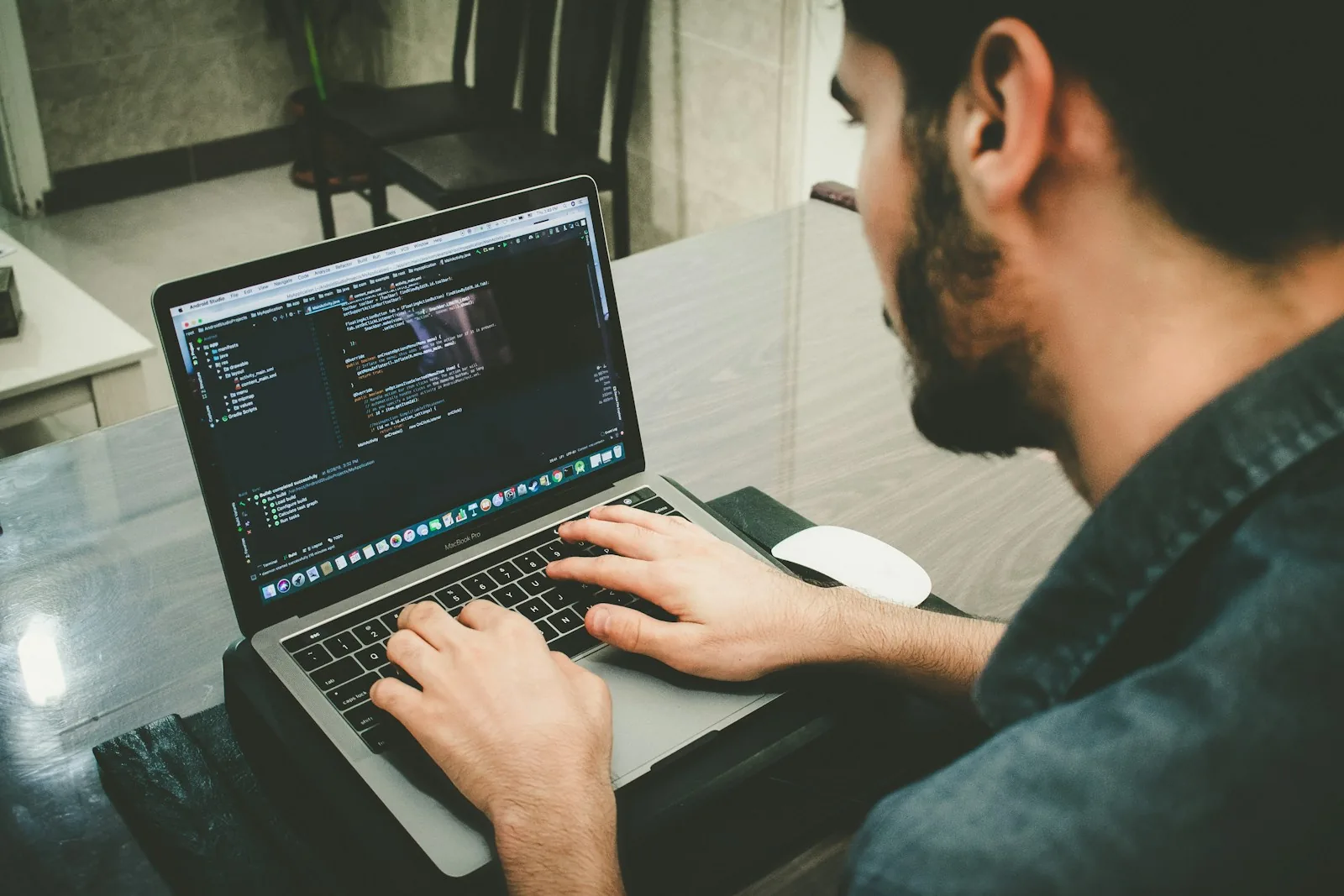 Developer reviewing AI-generated code on a laptop screen alongside a second monitor showing a code editor