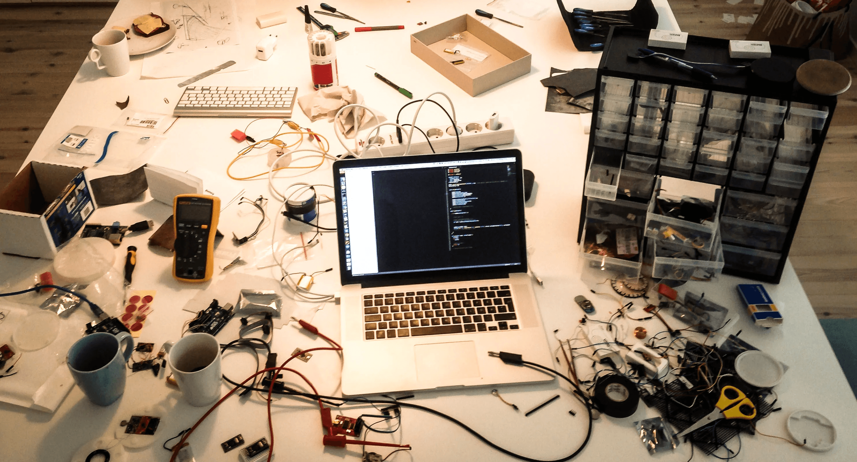 A messy table with a lot of prototyping tools and components.