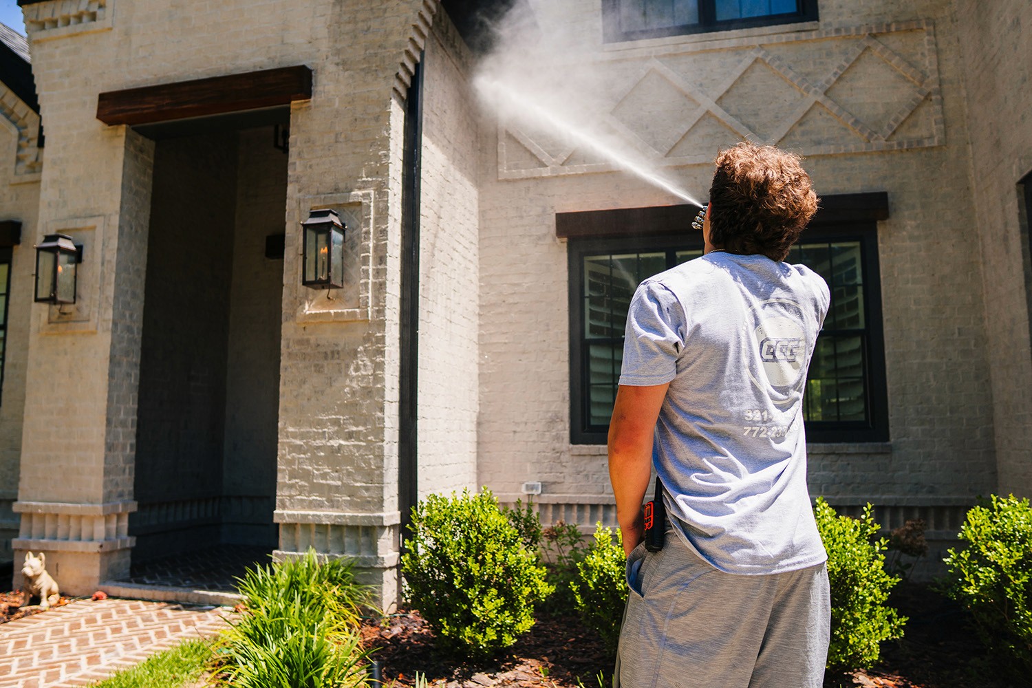 Worker powerwashing house