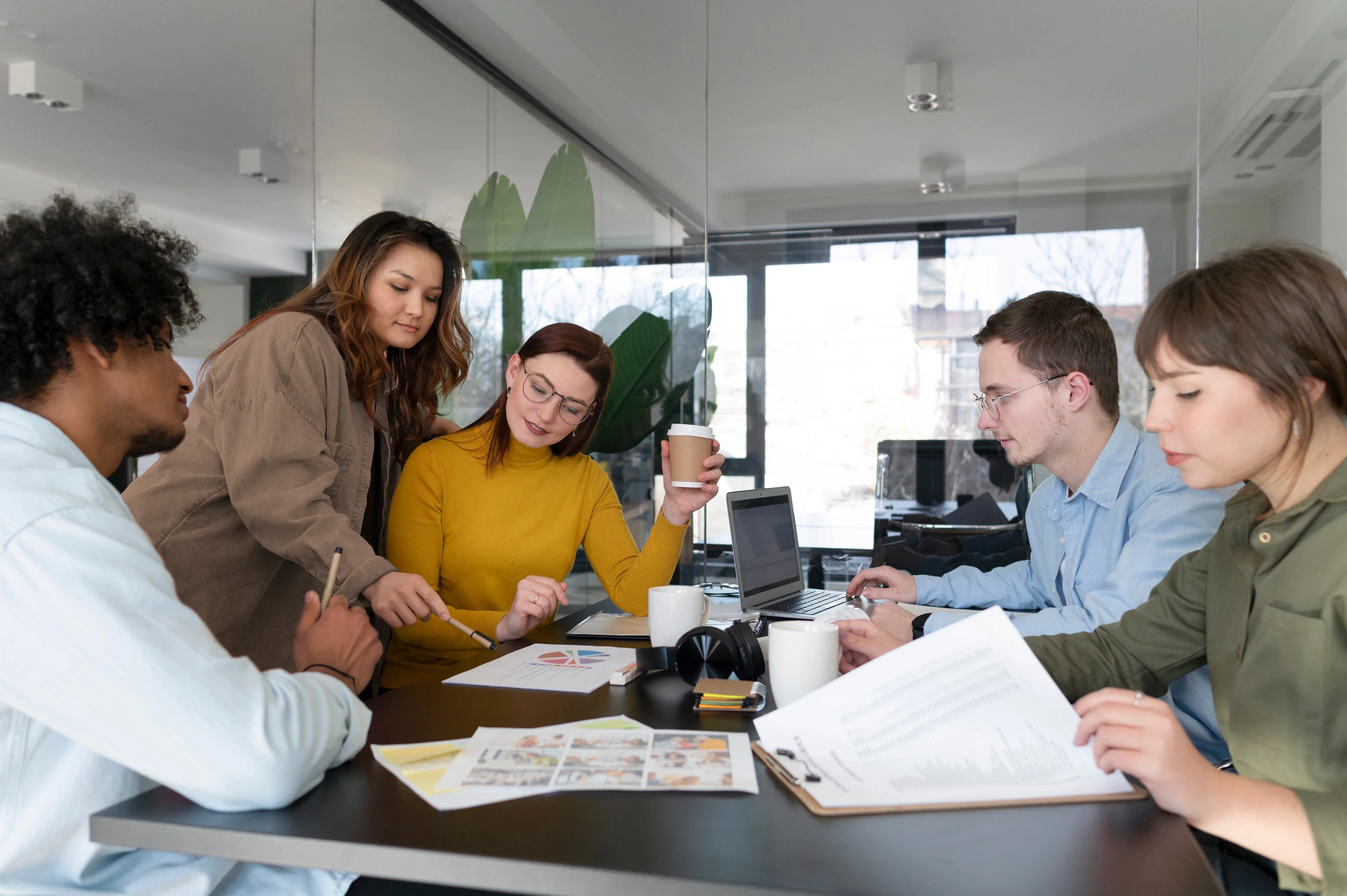 A professional colleague presenting a document in a folder to a coworker in a wheelchair during a collaborative meeting in a modern office.