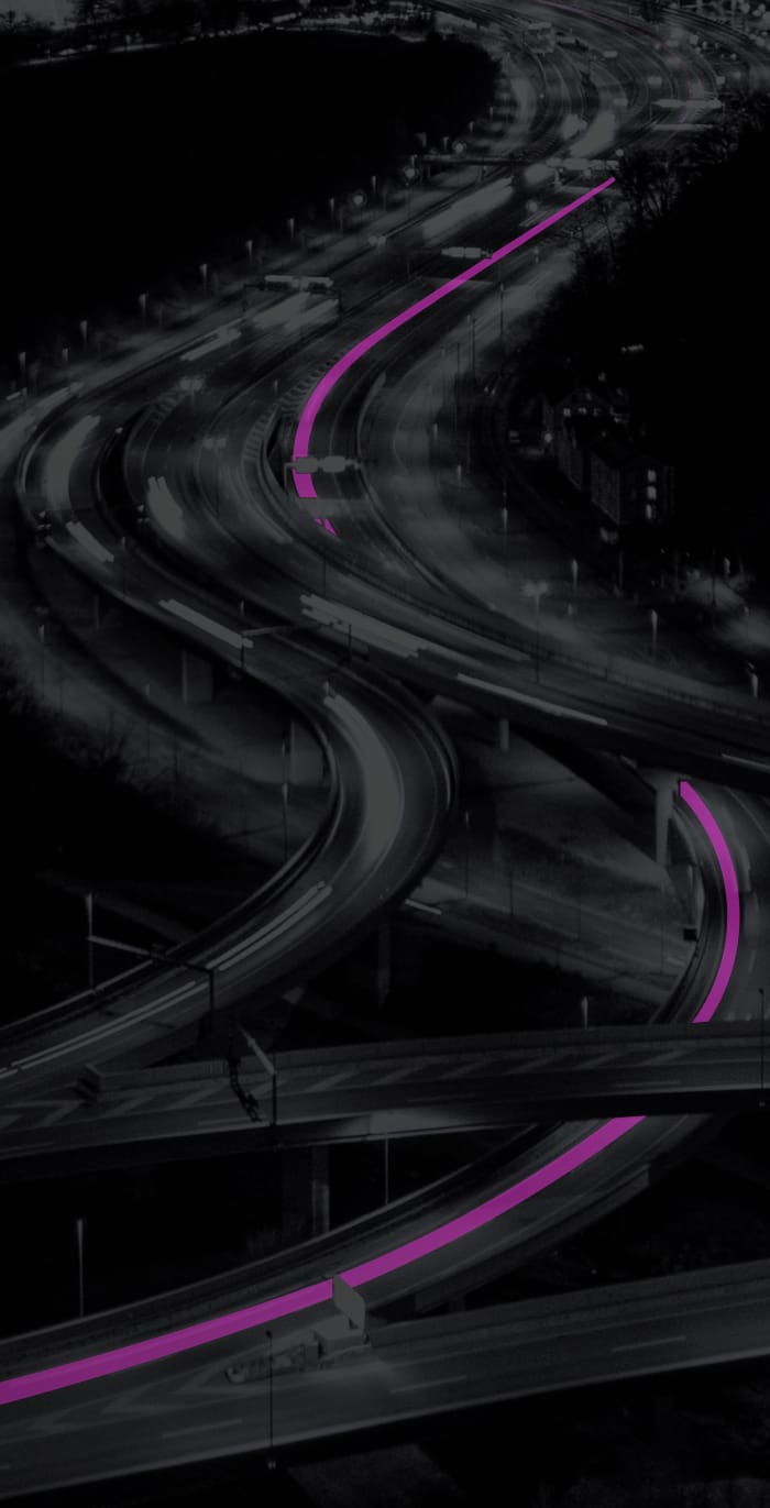 A busy highway at night with a route marked in pink