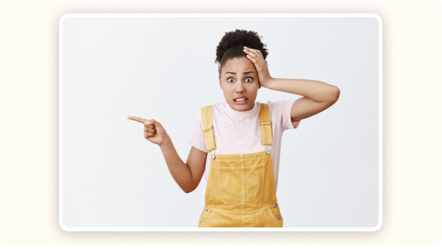 Femme surprise pointant quelque chose, main sur tête, expression inquiète.