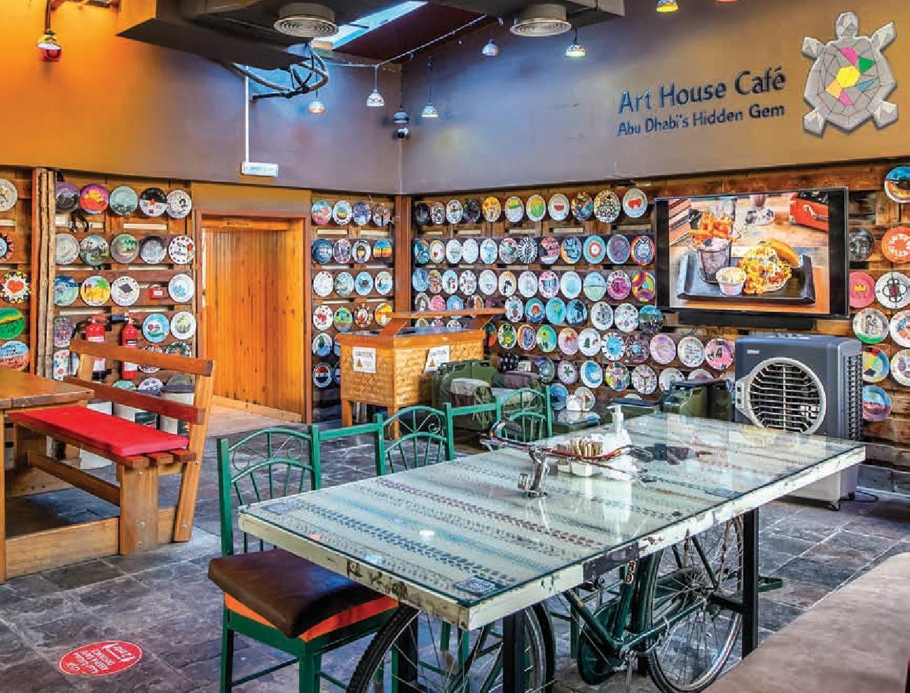 تصميم داخلي لمقهى مودرن يضم كاونتر مركزي وإضاءة دافئة مع جلسات مريحة، مما يوفر أجواءً هادئة وم مثالية لمن يبحث عن أرقى مقاهي في أبوظبي للعمل أو الاسترخاء.