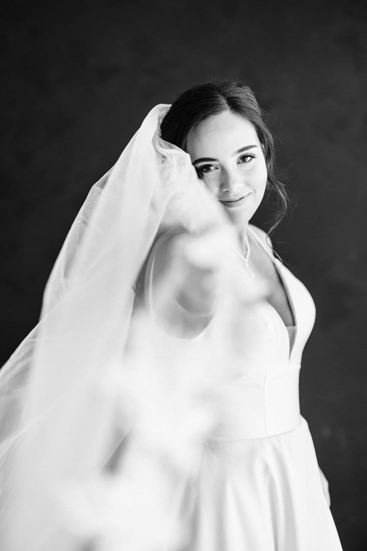 A black and white shot of a bride extending her veil during a bridal session at Revelator Studio, a natural light photography studio in Shreveport.