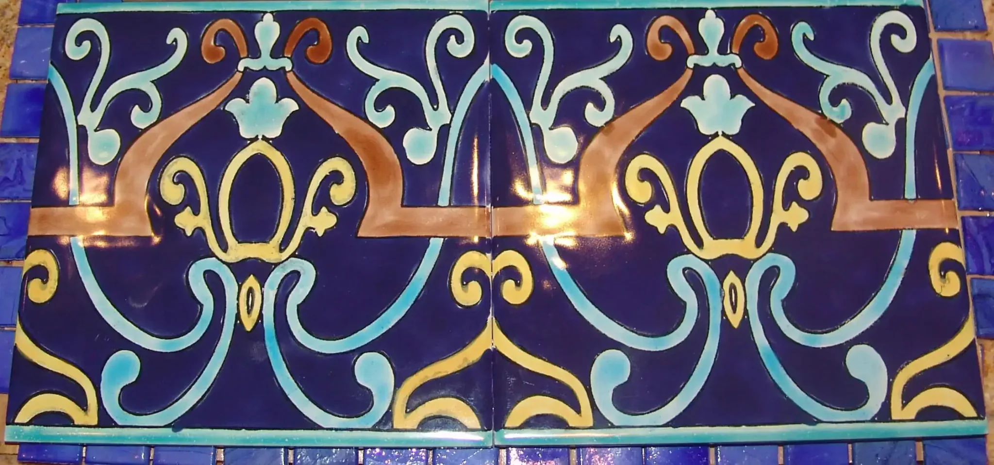 Blue mosaic pool tile with intricate gold and light blue patterns for luxury pool design.