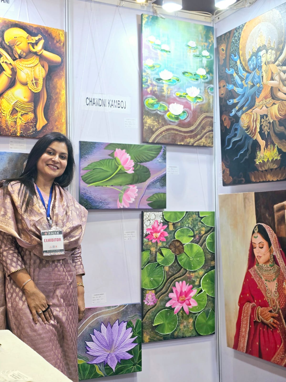 Mrs. Chandni Kamboj, founder of The Creative Pod, standing beside her paintings at an art event
